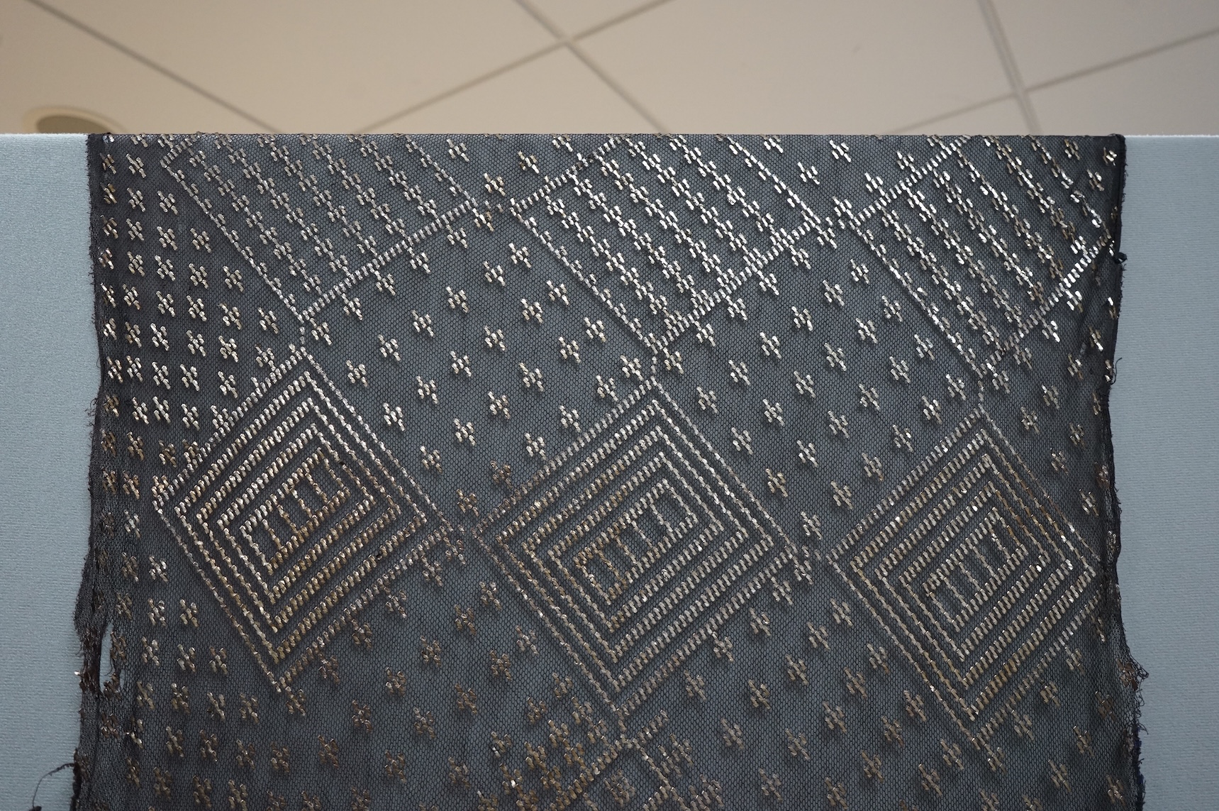A 1930’s Egyptian decorative metal on black net evening stole. Approximately 218cm long. Condition - the rolled edges are frayed but the colour and design are intact.
